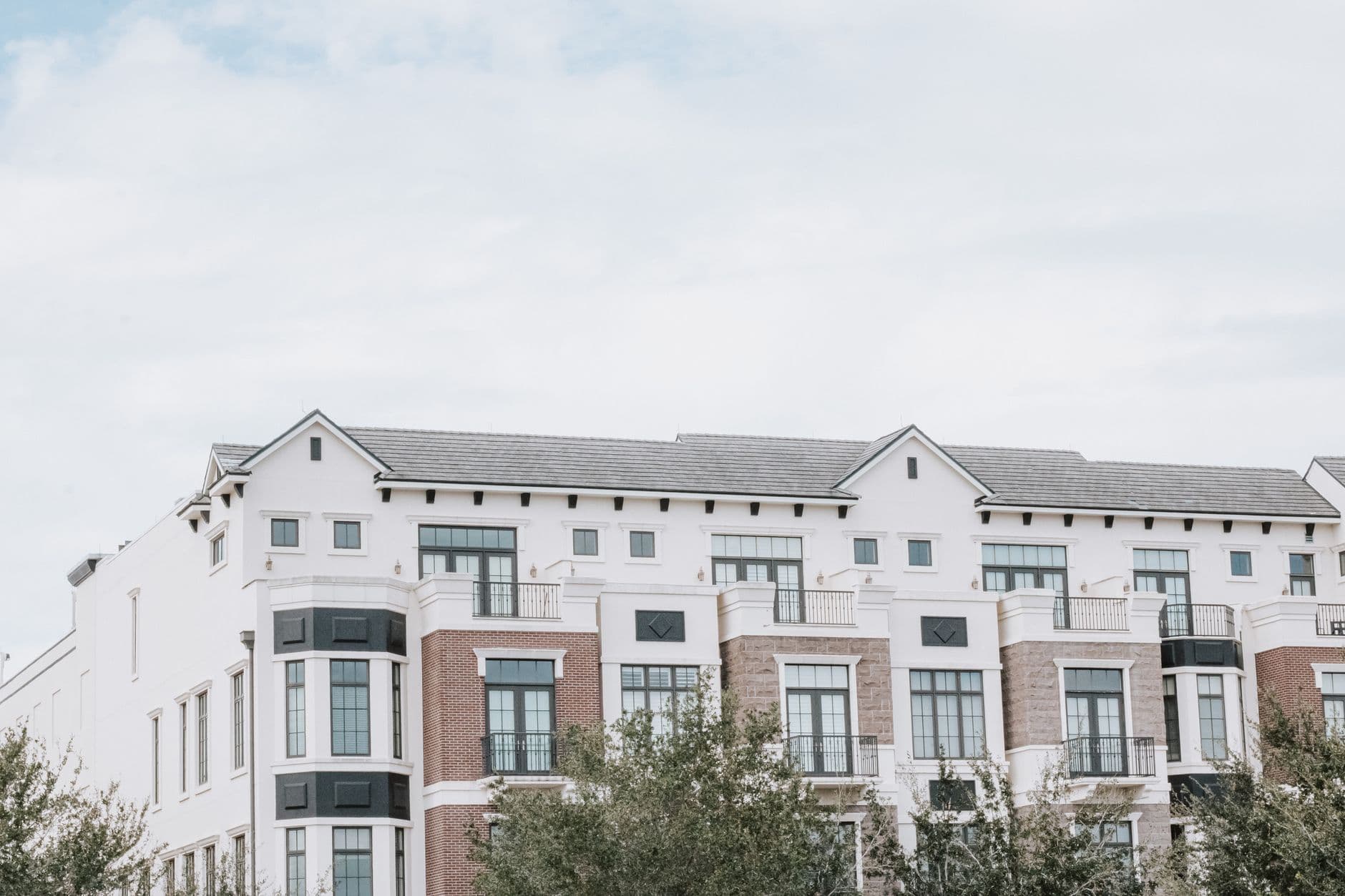 A stylish, multi-story luxury apartment building with a contemporary facade against a clear sky.